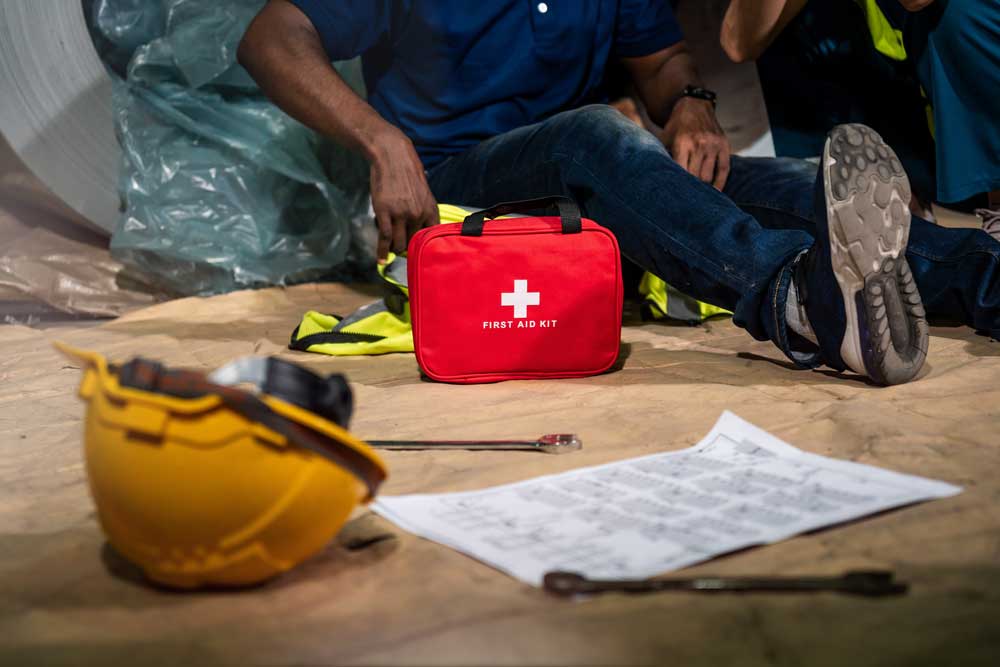 Worker being attended to by a first aider with a first aid kit on a construction site